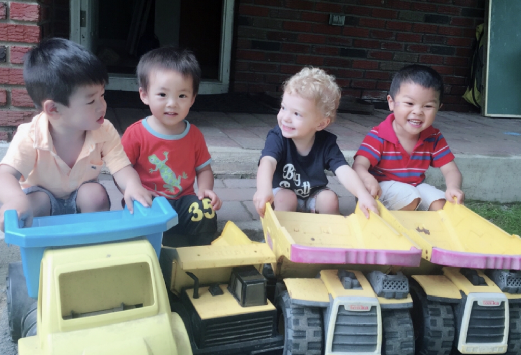 Boys sitting with their trucks together.
